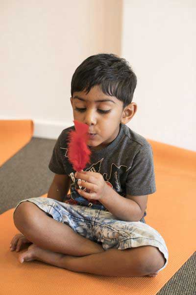 daycare student blowing on feather in kids yoga class