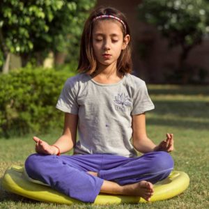 young girl in garden in yoga pose at daycare yoga class