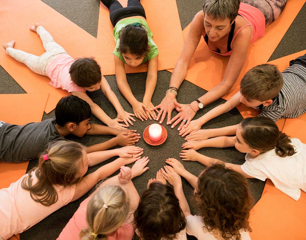 early learning kids with yoga teacher practising candle meditation