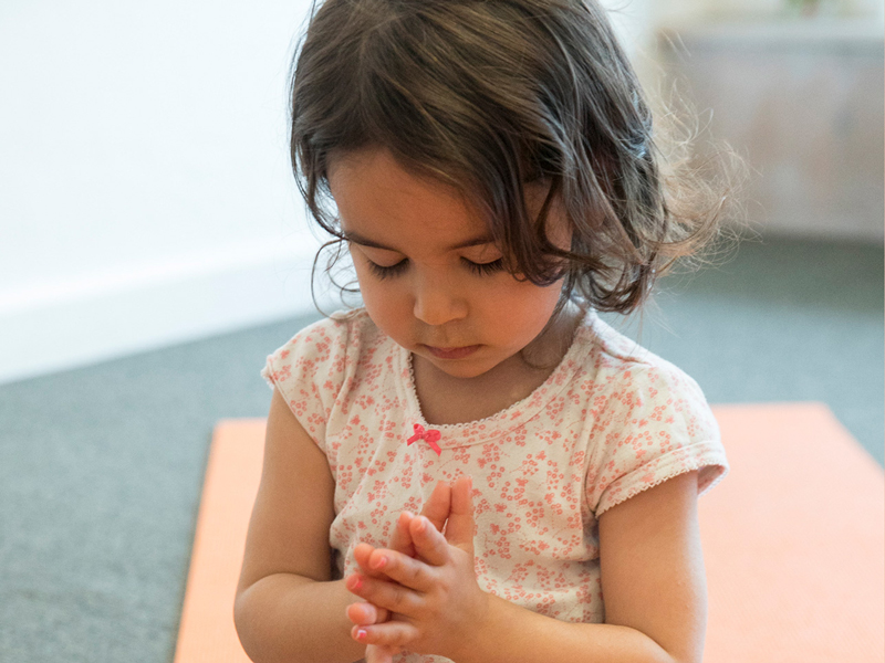 little girl at daycare in yoga class meditating