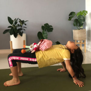 little girl with teddy on her tummy for at home yoga