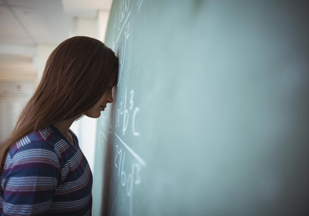 tired teacher standing at blackboard