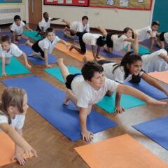 primary children in a yoga pose in the classroom